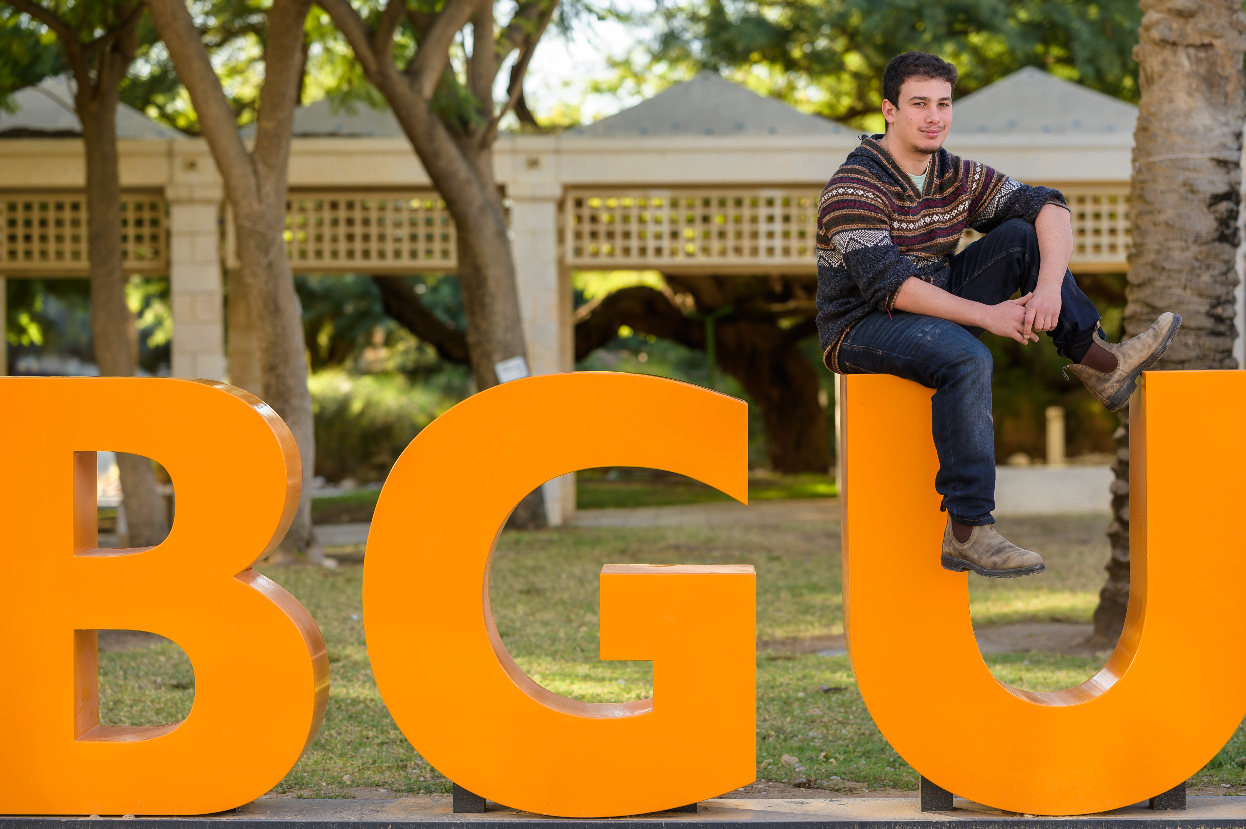 student sitting on BGU letters in Kreitman Plaza