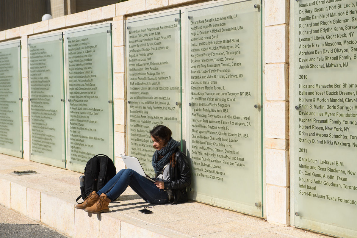 student sitting next to Ben-Gurion wall